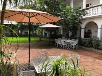 um pátio com uma mesa, cadeiras e um guarda-sol em NAH SAM CHAK La Casa Rosada em Tapachula