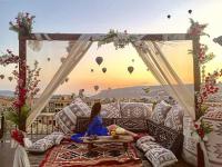 ギョレメにあるMilat Cave Hotelの風船を眺めながらソファに座っている女性