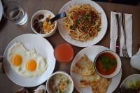 una mesa cubierta con platos de comida con huevos y pasta en Aspira One Sutthisan, en Bangkok