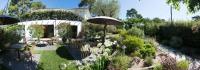 a garden with tables and chairs and an umbrella at Ferret Vigne - Villa Chambres d&#39;Hôtes in Cap-Ferret