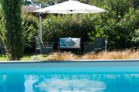 an umbrella and chairs next to a swimming pool at Ferret Vigne - Villa Chambres d&#39;Hôtes in Cap-Ferret