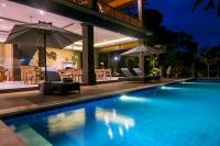 Ubud Hills Villas & Resort في أوبود: مسبح بكراسي ومظلات بجانب بيت
