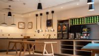 a bar in a restaurant with a table and chairs at Holiday Inn Express London Stansted Airport by IHG in Stansted Mountfitchet