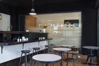 Un restaurante con mesas y taburetes en una habitación. en L'Aziz Suites - Near Aga Khan Hospital, en Nairobi