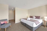 ein Schlafzimmer mit einem großen Bett und einem Stuhl in der Unterkunft Falcon&#39;s View Queenstown in Queenstown