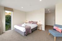 ein Schlafzimmer mit einem Bett und einem blauen Stuhl in der Unterkunft Falcon&#39;s View Queenstown in Queenstown