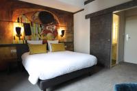 a bedroom with a bed with a painting on the wall at Hôtel la Capelle Millau in Millau