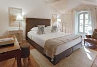 a bedroom with a large white bed and a desk at Baumanière - Les Baux de Provence in Les Baux-de-Provence