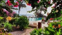 a swimming pool with people in the water and flowers at Porto Antigo 2 Beach Club in Santa Maria