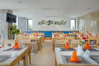 a dining room with tables and chairs with orange napkins at Cordial Beach Hotel Da Nang in Da Nang