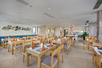 a restaurant with wooden tables and chairs with orange cones on them at Cordial Beach Hotel Da Nang in Da Nang