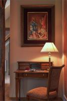 a desk with a lamp and a painting on the wall at Hotel Dvorac Jurjevec in Lekenik