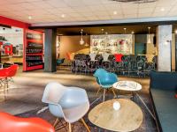 Un restaurante con sillas y mesas y un bar. en ibis Hotel Frankfurt Airport, en Kelsterbach