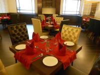 a dining room with tables and chairs with red napkins at Hotel Polo Towers Shillong in Shillong