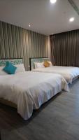 two beds in a hotel room with white sheets at The Loft Seaside Suites in Jinshan