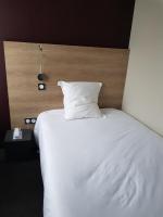 a white bed with a wooden headboard and a white pillow at Logis Hôtel A la Bonne Auberge in Laval