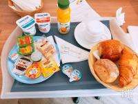 a tray with a plate of food and a basket of bread at Art Hotel Paris Est in Pantin