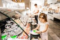 a little girl eating food in a restaurant kitchen at Barceló Maya Beach - All Inclusive in Xpu Ha
