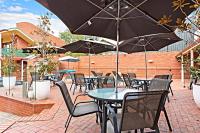 eine Terrasse mit Tischen und Stühlen mit Sonnenschirmen in der Unterkunft Comfort Inn Lady Augusta in Swan Hill