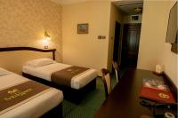 a hotel room with two beds and a desk and a table at Magus Hotel in Baia Mare