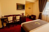 a hotel room with a bed and a desk and a table at Magus Hotel in Baia Mare