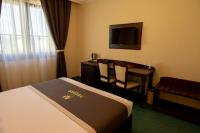 a hotel room with a bed and a desk and a television at Magus Hotel in Baia Mare