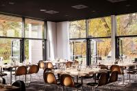 a dining room with tables and chairs and large windows at Comwell Kolding in Kolding