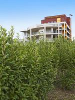 a building behind a hedge of bushes in front of a building at Tulip Inn Thionville Residences in Thionville