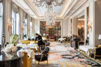 a dining room with tables and chairs and a chandelier at Four Seasons Hotel George V Paris in Paris