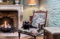 a black cat sitting on a chair in front of a fireplace at The Rookery in London
