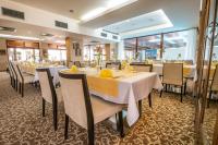 Un restaurante con mesas y sillas blancas y ventanas. en Wellness Hotel Diplomat, en Rajecké Teplice