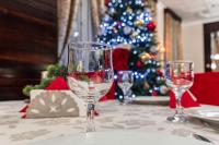 a table with two wine glasses on a table with a christmas tree at Pensiunea Splendid in Dorohoi