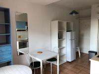 a kitchen with a white table and chairs and a refrigerator at 50m Plage T2 Grande Terrasse Vue Mer Climatisé Piscine Chauffée, Parking clos gratuit in Sanary-sur-Mer
