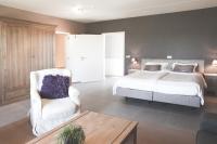 a bedroom with a bed and a white chair at B&amp;B Nieuwhof in Gistel