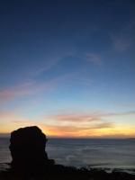 a sunset over the ocean with a rock in the foreground at Ming Jun Homestay in Eluan