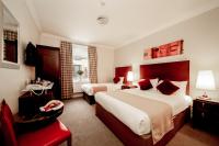 a hotel room with two beds and a red chair at White Sands Hotel in Portmarnock