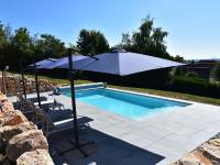 a swimming pool with an umbrella and two chairs at Gorgeous Holiday Home in Martigny le Comte with private Pool in Martigny-le-Comte