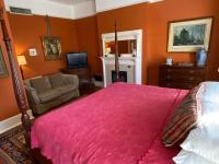 a bedroom with a bed and a chair and a fireplace at Foley House Inn in Savannah