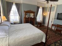 a bedroom with a bed and a tv and windows at Foley House Inn in Savannah