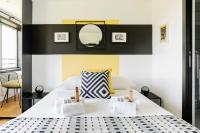 a bedroom with a white bed with a black and yellow wall at GuestReady - Charming studio in Issy-les-Moulineaux in Issy-les-Moulineaux