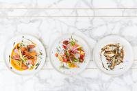 three plates of food on a white marble table at Kimpton Everly Hotel Hollywood by IHG in Los Angeles