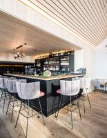 a bar with white bar stools in a room at HOLZGAUER HAUS in Warth am Arlberg