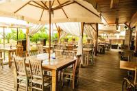 a restaurant with wooden tables and chairs and umbrellas at Life Resort na Beira do Lago em Brasília in Brasilia