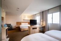 a hotel room with two beds and a flat screen tv at Beacon Hotel in Taichung