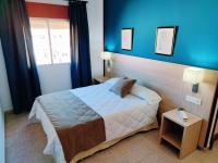 a bedroom with a bed with blue walls and a window at Hotel Catalán Puerto Real in Puerto Real