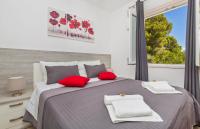 a bedroom with a bed with red pillows and a window at Apartments More in Sobra