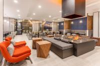 an open living room with orange chairs and a table at Holiday Inn & Suites Cedar Falls-Waterloo Event Ctr by IHG in Cedar Falls
