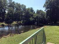eine Brücke über einen Fluss neben einem Feld in der Unterkunft The River Cottage in Pigeon Forge
