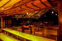 a restaurant with wooden tables and chairs and lights at Doola River Edge in Udawalawe