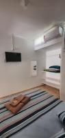 a white room with a bed with a tv on the wall at Hotel Nils in Itapoa